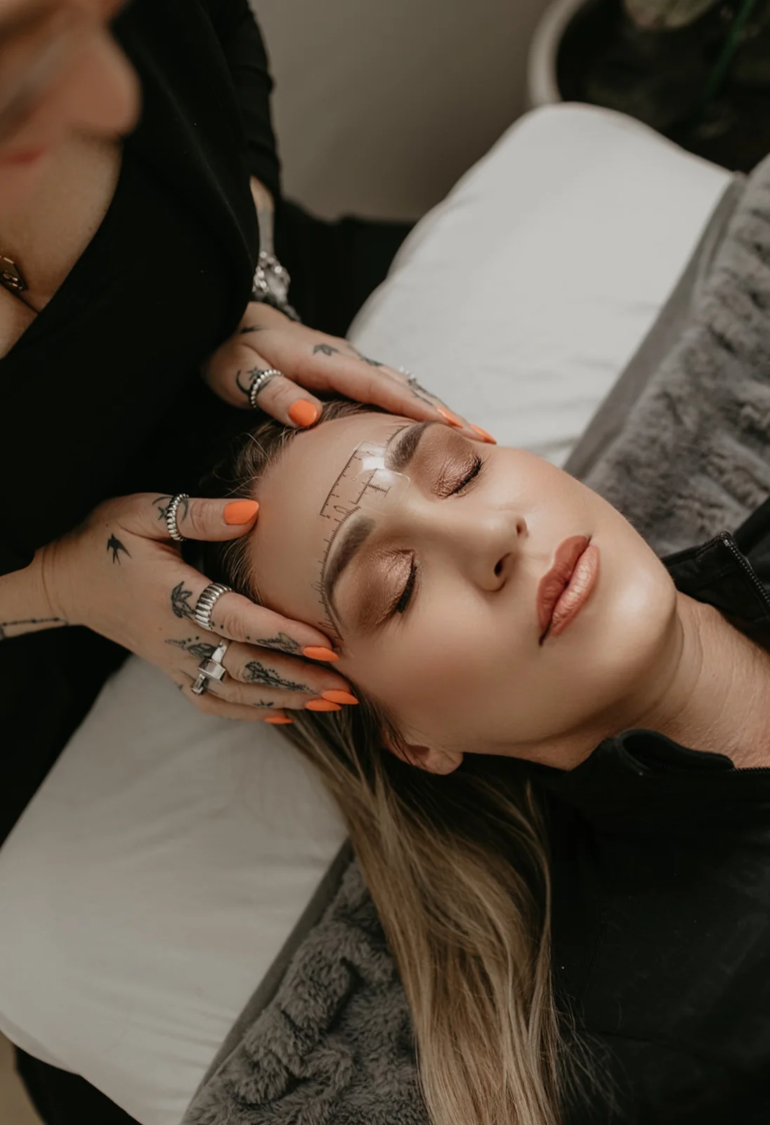 Cher's hands mapping a brow with a pencil, close up