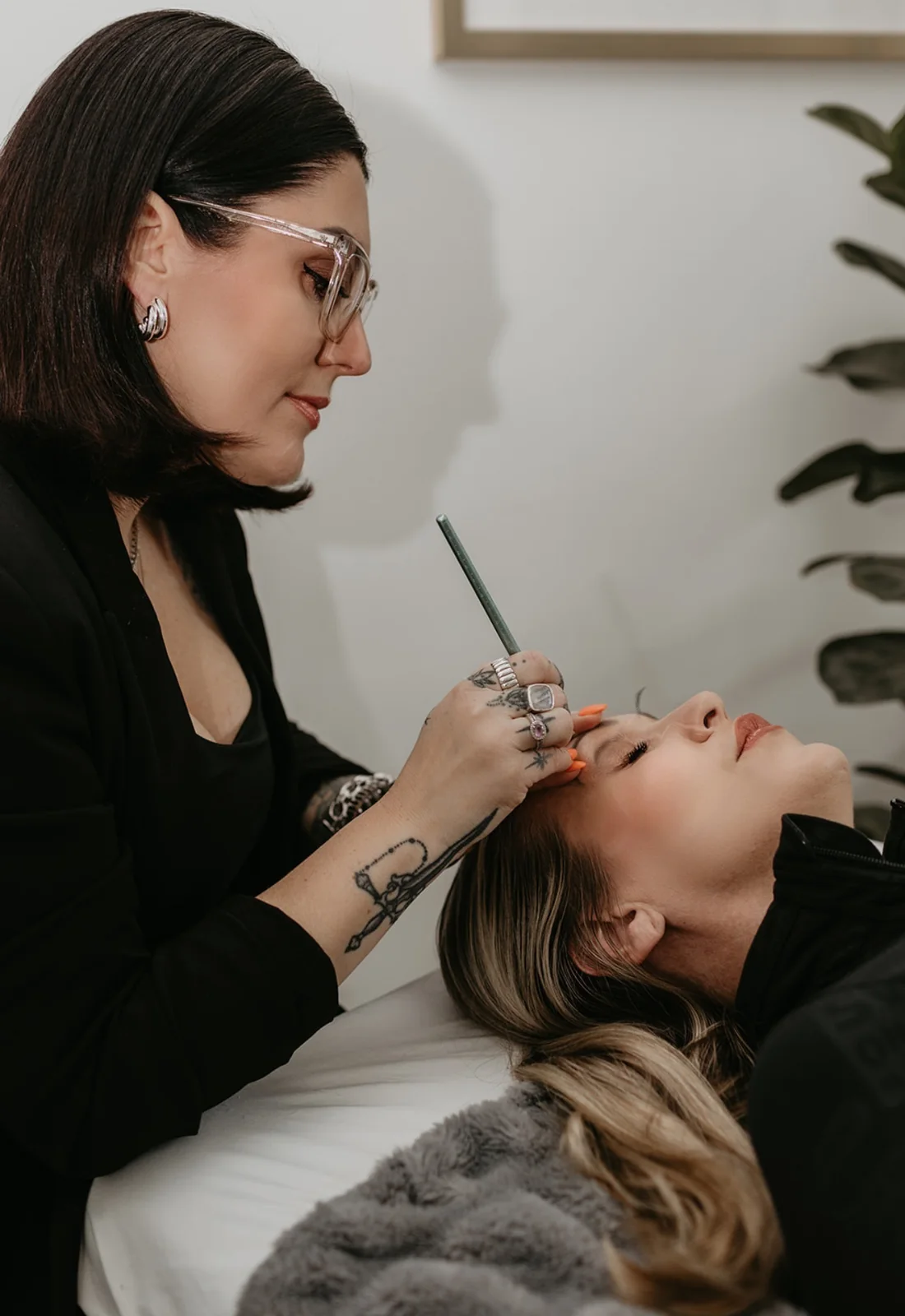 Cher mapping a client's brows, seen from the side