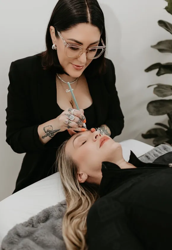 Cher microblading a client, tattooed hands in frame